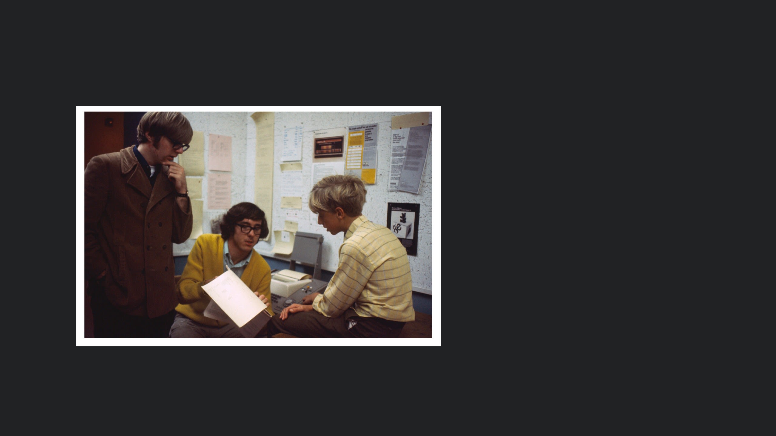 Paul Allen, Ric Weiland, and Bill Gates as teenagers looking at a computer printout.