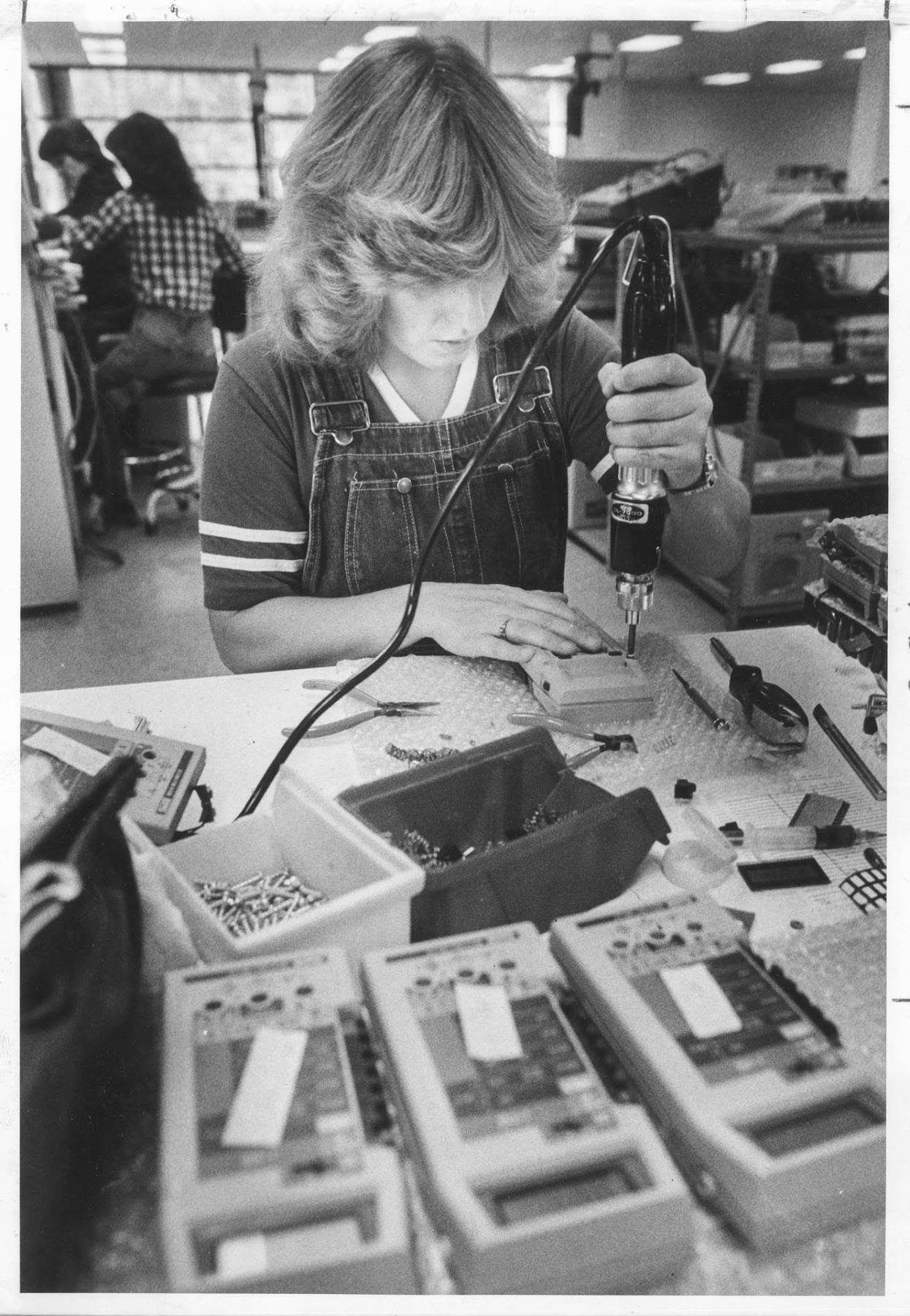 A person assembles electronics at a work bench.