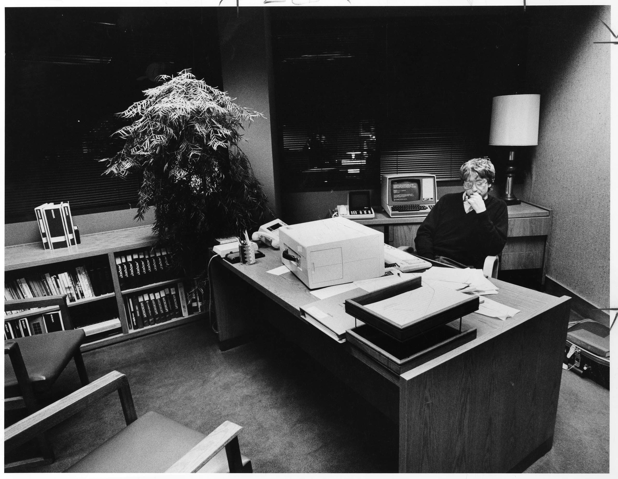 A dramatic photograph of a young Bill Gates sitting behind a desk.